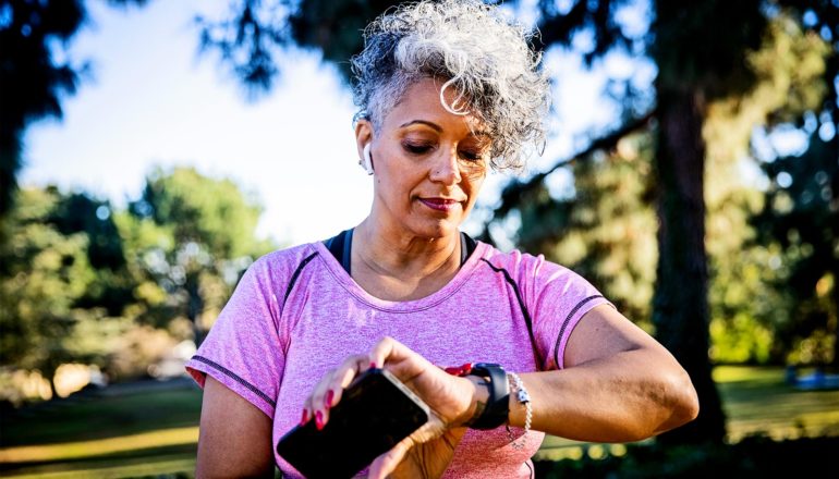 A woman checks her smartwatch while walking in the park