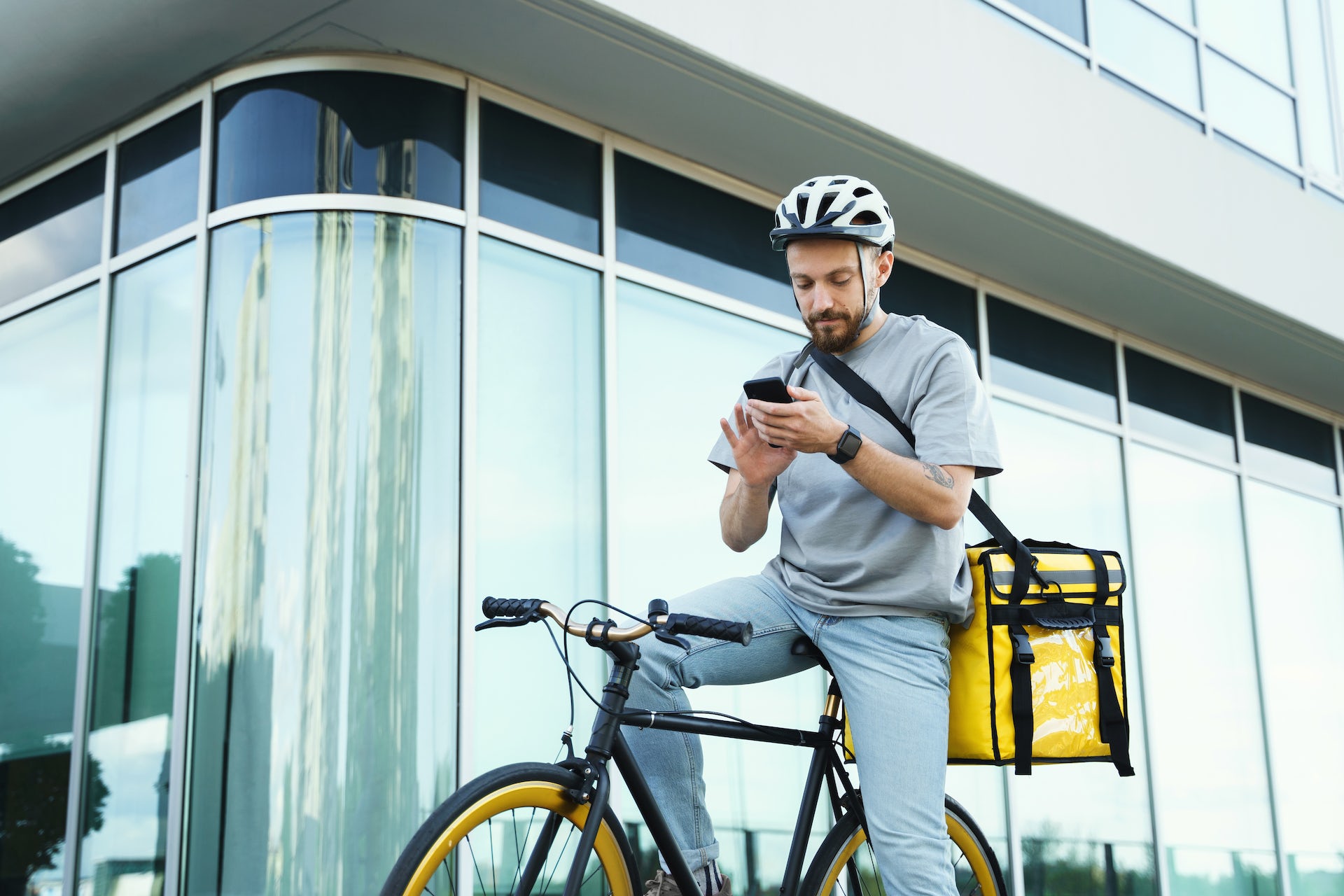 Express food delivery courier riding bicycle with insulated bag behind his back