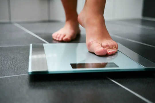 A person steps onto bathroom scales.