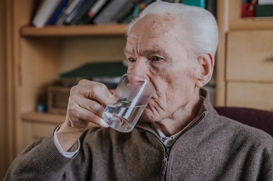 man drinking clear liquid from a cup
