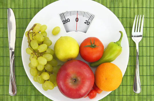 Fruits and vegetables on a dinner plate that looks like a bathroom scale.