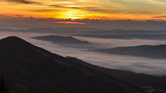 photo of a sunrise with fog in the valley below