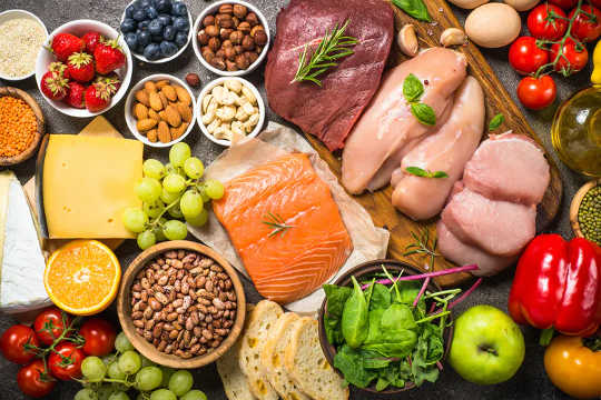 An assortment of healthy foods, including salmon, berries, cheese, and legumes.
