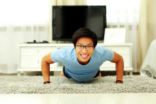 Smiling man doing pushups at home 