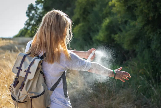 woman spraying insect repellent