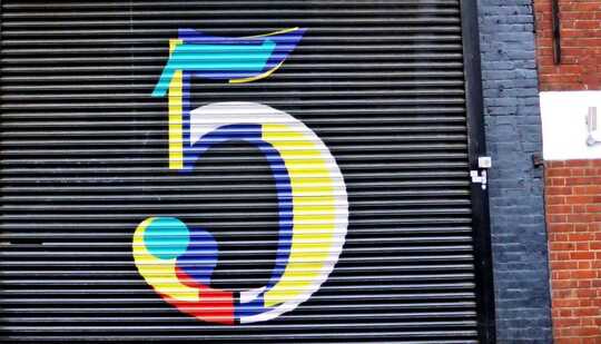 A colorful number 5 is painted on a store's black door shutter