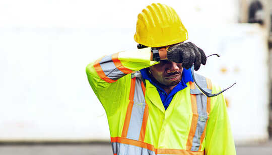 A construction worker wipes his forehead in the heat