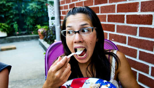 A woman takes a bite of food at a backyard party