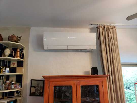 Mini split heat pump indoor unit mounted over a fireplace.