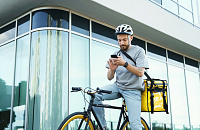 Express food delivery courier riding bicycle with insulated bag behind his back